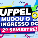 Banner com design vibrante e o texto centralizado: "UFPel mudou o ingresso do 2º semestre!". Fundo azul com ícones geométricos e silhueta de prédios universitários.